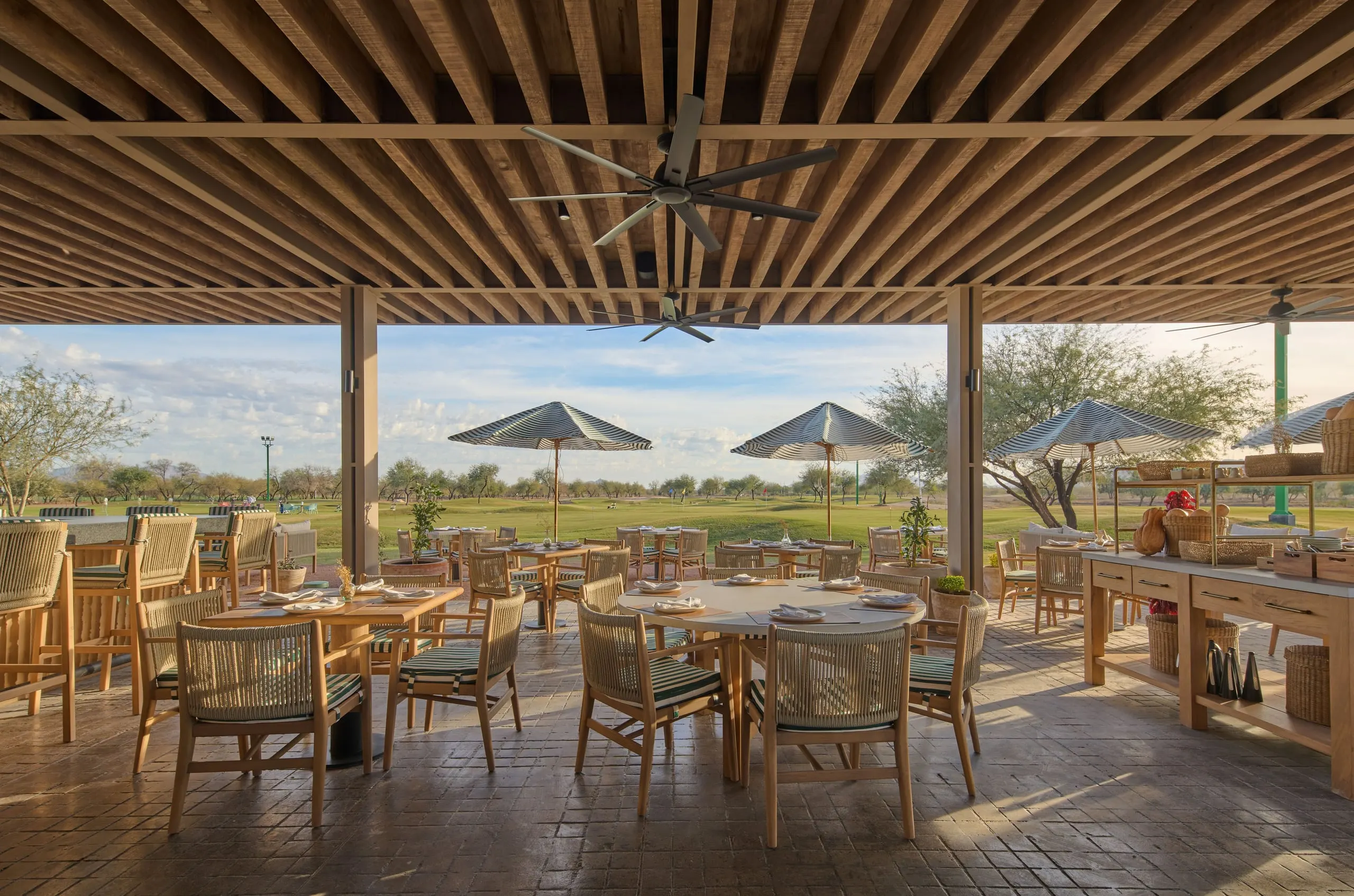 Maderas: terraza de restaurante bajo un techo de vigas de madera, con vista a un campo verde