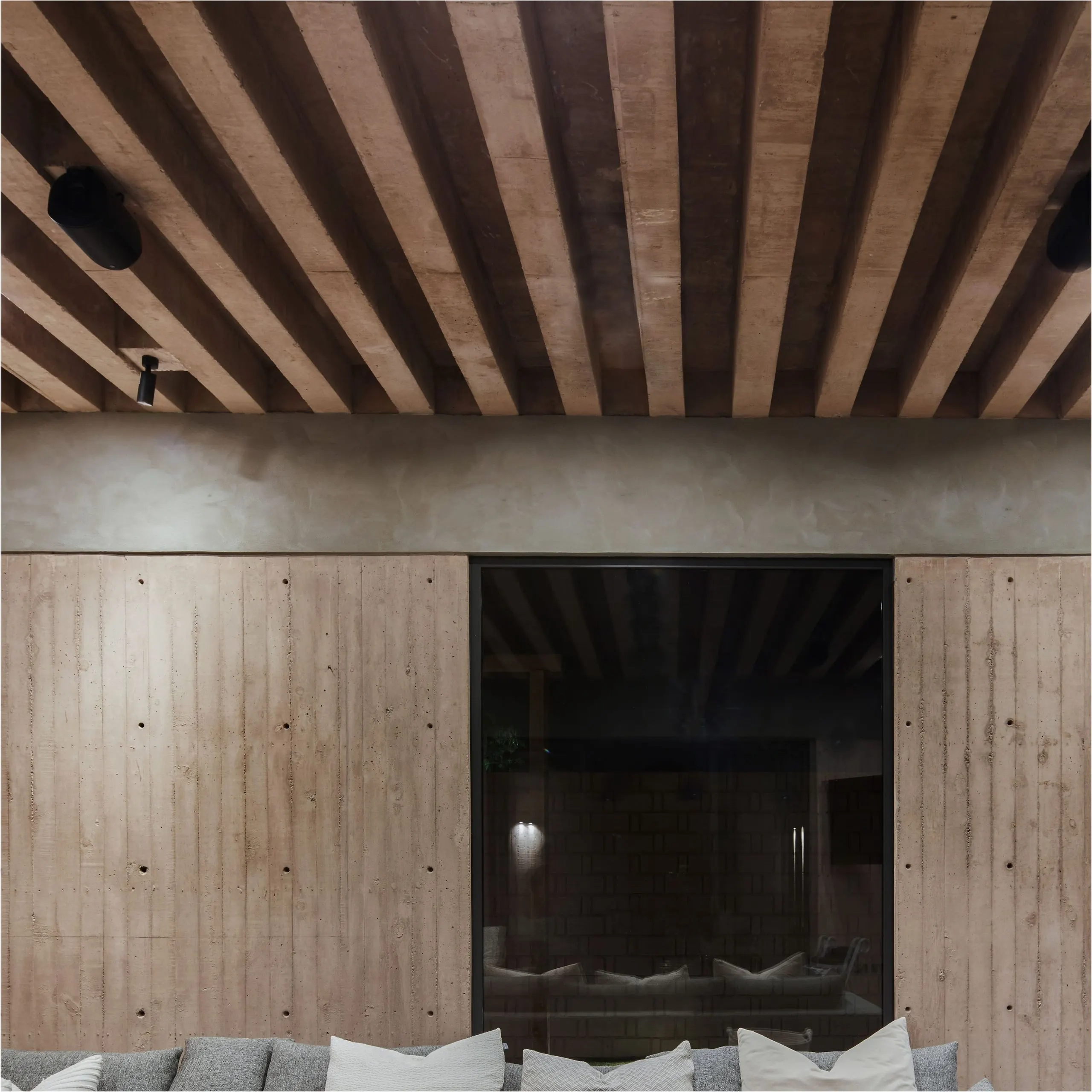 Casa Edena: muro de concreto bajo un techo de vigas de madera